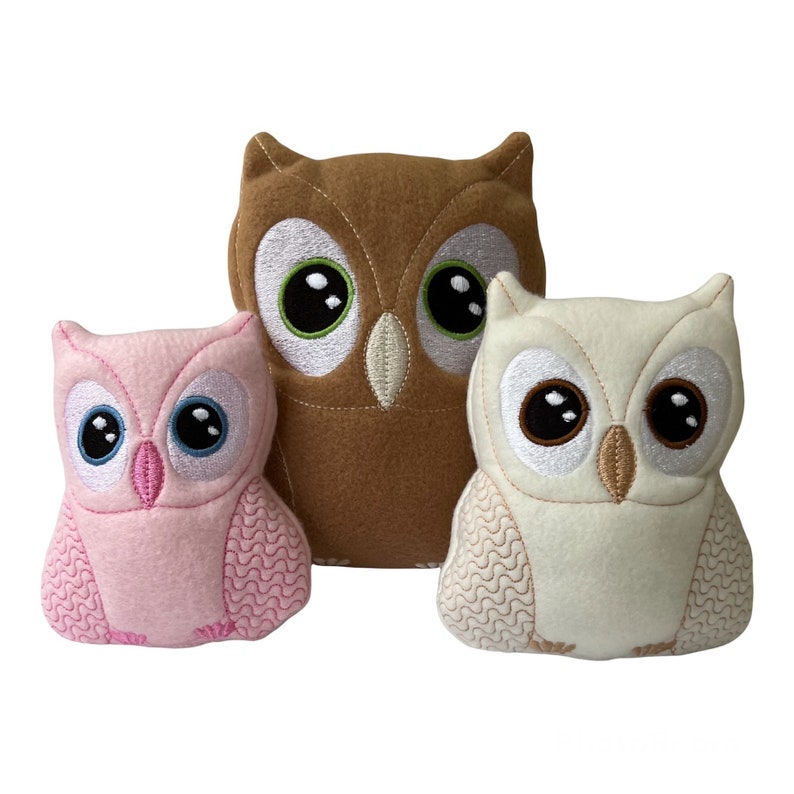 May include: Three plush owl toys, one brown, one white, and one pink. The owls have embroidered eyes and beaks.