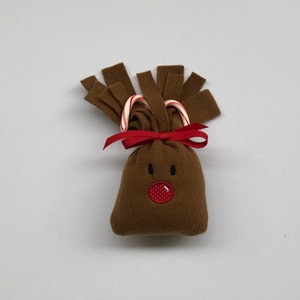 May include: A brown felt reindeer ornament with candy cane antlers and a red embroidered nose.