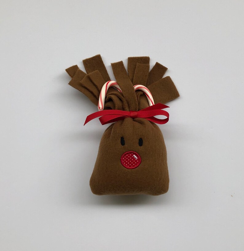 May include: A brown felt reindeer ornament with candy cane antlers and a red embroidered nose.