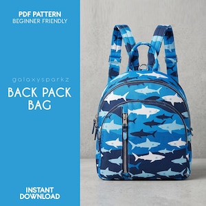 May include: A backpack featuring a repeating shark pattern in shades of blue and white. The bag has a top handle, two adjustable shoulder straps, and a front zippered pocket. Text on the left reads: PDF PATTERN BEGINNER FRIENDLY galoxysparkz BACK PACK BAG INSTANT DOWNLOAD.