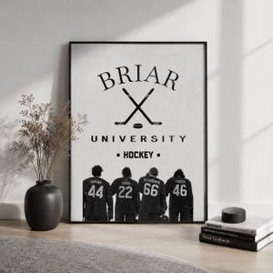 Może przedstawiać: Czarny oprawiony wydruk z napisem "Briar University Hockey" i skrzyżowanymi kijami hokejowymi. Czterech hokeistów z numerami na koszulkach widać od tyłu. Czarny krążek hokejowy i książki na pierwszym planie.