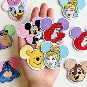 Puede incluir: Una colección de parches bordados con personajes de Disney. Los parches incluyen a Mickey Mouse, Minnie Mouse, Ariel, Cenicienta, Winnie the Pooh, Daisy Duck, Chip, Buzz Lightyear y Eeyore. Cada parche tiene un diseño y esquema de color únicos.