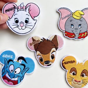 以下が含まれることがあります： ディズニーキャラクターの刺繍ワッペンコレクション。マリー、ダンボ、バンビ、ジーニー、シンバが含まれています。各ワッペンは白い縁取りと鮮やかな色で、衣類やアクセサリーの装飾に最適です。