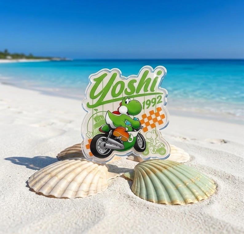 Peut inclure: Un porte-cl&eacute; en acrylique transparent repr&eacute;sentant le personnage Yoshi vert sur une moto. Le motif inclut le texte Yoshi et 1992 en vert, ainsi qu'un motif &agrave; damier orange. L'objet est pr&eacute;sent&eacute; devant un arri&egrave;re-plan d'oc&eacute;an bleu vif.