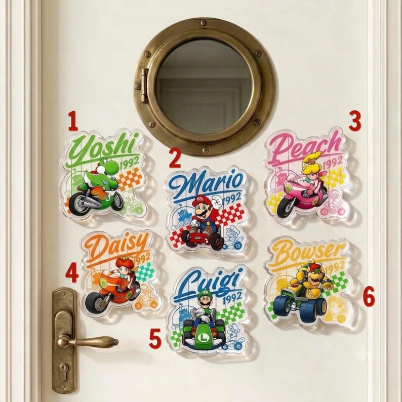 Peut inclure: Six plaques d&eacute;coratives en acrylique transparent repr&eacute;sentant les personnages Nintendo Yoshi, Mario, Peach, Daisy, Luigi et Bowser dans des v&eacute;hicules de course. Chaque plaque affiche le nom, l'ann&eacute;e 1992 et un motif &agrave; damier sur une porte.