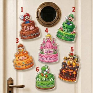 May include: Six decorative wall signs featuring Super Mario characters on cakes or pipes. Each sign displays the name Liam and the text Happy 1st Birthday. Characters include Mario, Luigi, Daisy, Princess Peach, Bowser, and Yoshi in vibrant colors.