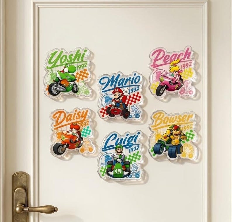 Peut inclure: Un ensemble de cinq autocollants muraux en acrylique repr&eacute;sentant les personnages Nintendo Yoshi, Mario, Peach, Daisy, Luigi et Bowser dans des v&eacute;hicules de course. Chaque autocollant inclut le nom du personnage, l'ann&eacute;e 1992 et des motifs &agrave; damier.