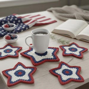 May include: A white mug filled with a dark liquid sits on a star-shaped coaster. The coasters are red, white, and blue, with a crochet design. Other coasters are scattered around, along with a small bowl of berries and a folded American flag.