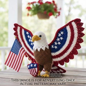 May include: A crocheted bald eagle with outstretched wings, featuring red, white, and blue details. It holds a small American flag and a shield. The text at the bottom reads: "THIS IMAGE IS FOR ADVERTISING ONLY. ACTUAL PATTERN MAY VARY."