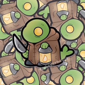 May include: A cartoon sticker featuring a green creature with a large yellow eye, wearing a brown hooded cloak and holding a silver knife and a lantern with a yellow flame. The sticker has a white border and a repeating pattern.