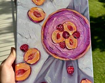 May include: An oil painting on canvas depicts a still life of fruit. The artwork features a purple plate with sliced peaches and raspberries, surrounded by scattered peaches and raspberries. The background is a light gray cloth.
