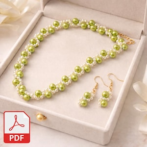 May include: A beaded jewelry set featuring a necklace and earrings. The necklace and earrings are made with white and light green beads. The set is displayed in a white jewelry box with a PDF icon in the corner.