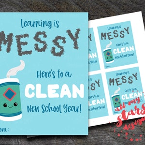 Puede incluir: Una tarjeta azul con el texto "Learning is MESSY Here's to a CLEAN New School Year!" y una ilustración de dibujos animados de una lata con una cara. La tarjeta tiene el texto "from:" en la parte inferior.