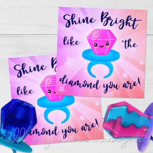 May include: Two pink and blue cards with a diamond ring design and the text "Shine Bright like the diamond you are!"  The cards are next to two blue and pink lollipops with a ring design.