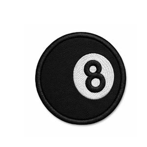May include: Embroidered patch featuring the number 8 from a pool ball. The patch is round with a black background and a white number 8. The border is black. The patch is likely for clothing or accessories.