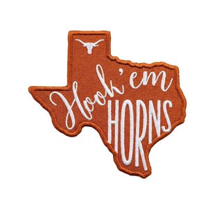 May include: An embroidered patch in the shape of Texas, in burnt orange with a white outline. The patch features the words "Hook 'em HORNS" in white script and block letters, and a white longhorn symbol.