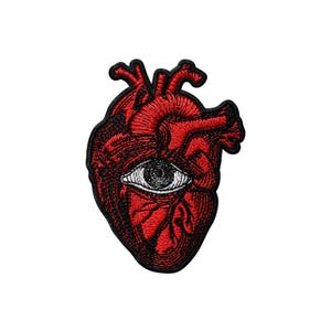 May include: Embroidered patch featuring a red anatomical heart with a white eye in the center. The patch has a black border and detailed stitching, suitable for jackets, bags, or other fabric items.