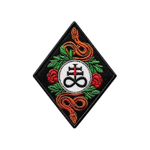 Può includere: Toppa nera a forma di diamante con un disegno di serpente arancione. Il disegno centrale comprende un cerchio bianco con un simbolo nero, rose rosse e foglie verdi. La toppa ha un aspetto ricamato.
