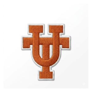 Puede incluir: Parche bordado con una letra "U" estilizada en naranja y blanco, con un diseño en forma de cruz. El parche tiene un borde blanco, ideal para ropa o accesorios.