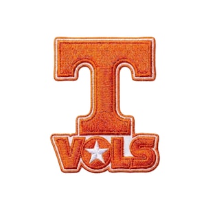 May include: An orange embroidered patch with a white border, featuring the letter "T" and the word "VOLS". A white star is in the center of the "O". The patch is on a white background.