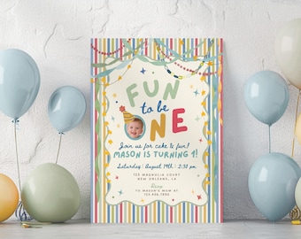 Puede incluir: Una tarjeta de invitación de cumpleaños rectangular con un borde de rayas verticales en rojo, azul, amarillo y verde. El centro muestra el texto "FUN to be ONE" con una foto circular de un niño con un gorro de fiesta y los detalles.