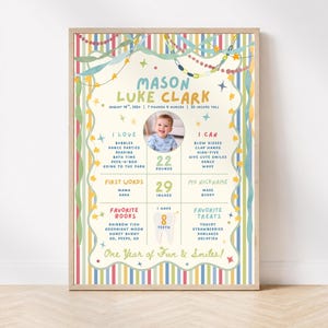 May include: A rectangular milestone poster featuring a colourful striped border with hanging garlands and stars. It displays the name Mason Luke Clark, birth details, a central photo of a baby, and sections for interests, skills, words, and favourites.
