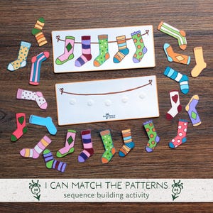May include: A wooden educational toy featuring colorful socks with various patterns. The set includes a board with a clothesline and individual sock cutouts. The text "I CAN MATCH THE PATTERNS sequence building activity" is at the bottom.