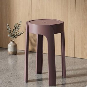 Puede incluir: Un taburete moderno de color malva con un asiento circular y cuatro patas rectas. El taburete está hecho de un material sólido y tiene un diseño minimalista. El taburete mide aproximadamente 43 cm de altura.