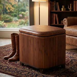 May include: A brown leather-topped ottoman with a vertical slatted wood base. The ottoman is square and sits on short, dark-coloured feet. Two brown leather boots are next to the ottoman on a patterned rug.