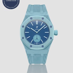 Könnte beinhalten: Eine hellblaue Armbanduhr mit dunkelblauem Zifferblatt und hellblauem Armband. Das Zifferblatt hat weiße Zeiger und Markierungen. Der Text "AP swatch" ist auf dem Zifferblatt sichtbar. Der Text "COMING SOON" befindet sich in einem Kreis oben links.