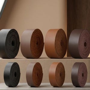 Può includere: Una collezione di rotoli di pelle in varie tonalità di marrone e nero. I rotoli sono disposti ordinatamente su una mensola, mostrando i diversi colori e le trame del materiale. L'immagine evidenzia la varietà di opzioni in pelle disponibili.