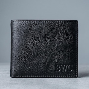 May include: A black leather wallet with a textured finish. The rectangular wallet has the embossed initials "BWC" on the lower right. The wallet is closed and appears to be unused.