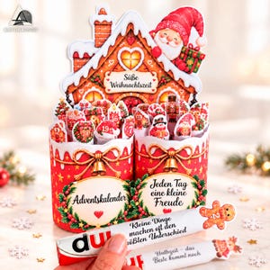 May include: A red and white cardboard advent calendar shaped like a gingerbread house with a Santa figure, numbered cutouts from 1 to 24, and German text including "Süße Weihnachtszeit," "Adventskalender," and "Jeden Tag eine kleine Freude."