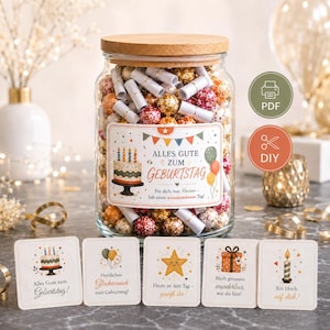 Pode incluir: Um frasco de vidro transparente com tampa de madeira cheio de pequenos rolos de papel e bolas decorativas coloridas. O rótulo apresenta uma ilustração de bolo de aniversário e o texto ALLES GUTE ZUM GEBURTSTAG. Cinco pequenos cartões estão à frente.