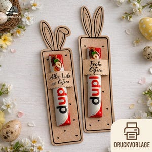 May include: Two Easter gift tags with bunny ears, each holding a chocolate bar. The tags are made of brown cardstock and feature the text "Alles Liebe zu Ostern" and "Frohe Ostern". The background includes Easter eggs and flowers.