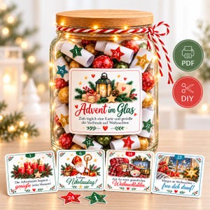 Könnte beinhalten: Ein klares Glasgefäß mit Holzdeckel und Lichterkette, gefüllt mit gerollten Papierkarten sowie roten und goldenen Kugeln. Das Etikett zeigt Advent im Glas mit Laterne und Geschenken. Vier quadratische Karten mit Weihnachtsmotiven liegen davor.