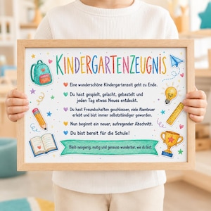 Könnte beinhalten: Ein gerahmter Druck mit dem Titel Kindergartenzeugnis, verziert mit bunten Illustrationen von Rucksack, Stift, offenem Buch, Glühbirne, Lineal und Pokal, sowie deutschem Text, der den Abschluss der Kindergartenzeit und den Schulstart feiert.