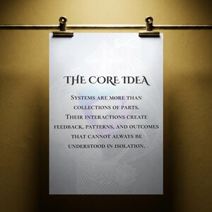 Op de afbeelding: Een witte rechthoekige poster die aan een gouden metalen stang met twee clips hangt. De poster bevat de tekst: THE CORE IDEA. SYSTEMS ARE MORE THAN COLLECTIONS OF PARTS. THEIR INTERACTIONS CREATE FEEDBACK, PATTERNS, AND OUTCOMES THAT CANNOT ALWAYS BE UNDERSTOOD IN ISOLATION.
