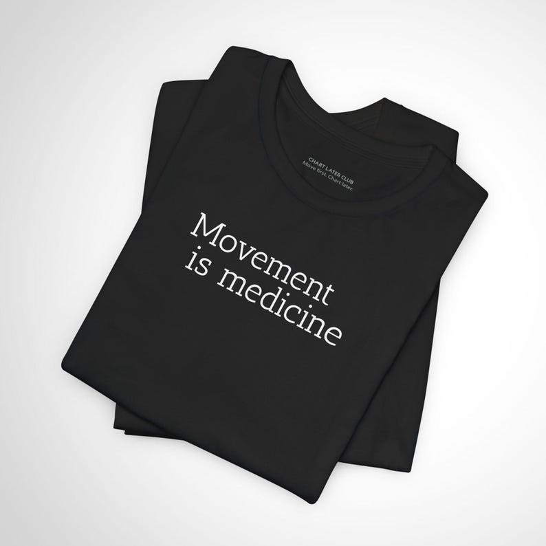 May include: Black t-shirt with the text "Movement is medicine" in white. The shirt is folded and has a crew neck. The brand name "CHART LATER CLUB" is printed on the inside collar.