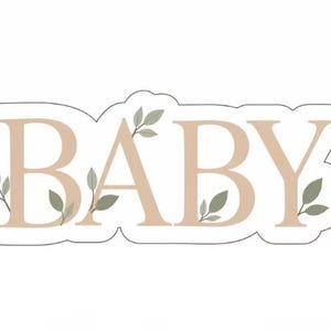 May include: A die-cut sticker featuring the word BABY in large, light tan serif capital letters. The design is accented with small, sage green leaf sprigs emerging from behind and around the letters, all outlined with a thin white border.