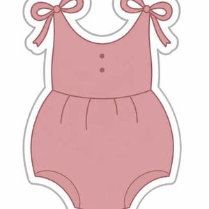 Può includere: Un body rosa per neonati con un fiocco su ogni spallina. Il body ha uno scollo arrotondato, due piccoli bottoni e una vita arricciata. Il contorno del body è bianco con un bordo grigio.