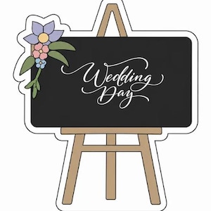 May include: A chalkboard sign with the words "Wedding Day" in elegant script. The sign is on a wooden easel and decorated with a floral arrangement in shades of purple, pink, and green. The overall design is a charming and decorative wedding theme.