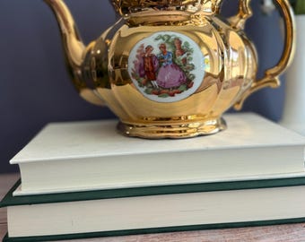 Tetera vintage de cerámica Crown Pottery, con diseño de pareja de enamorados victoriana en color dorado.