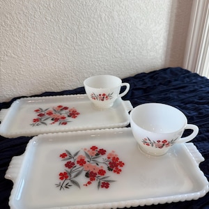 May include: Two white milk glass snack sets. Each set includes a rectangular tray with scalloped edges and a handle, and a teacup. The trays and cups are decorated with a floral design in red and pink.