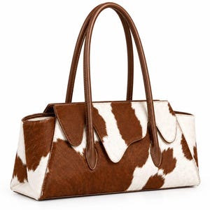 May include: A rectangular handbag featuring a brown and white cowhide pattern with a textured finish. The bag includes two tall, smooth brown leather handles and a flap closure with a pointed centre detail, showcasing a structured design.