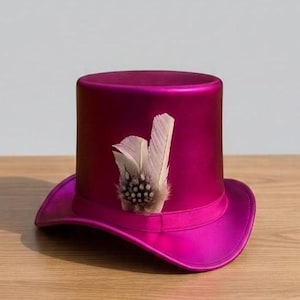 May include: A magenta top hat with a wide brim and a decorative band. The hat is adorned with a cluster of feathers in shades of white and brown. The hat is sitting on a wooden surface.