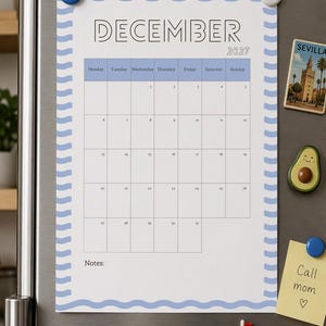 Puede incluir: Una página de calendario de diciembre de 2027 con un borde ondulado azul claro. El calendario presenta una cuadrícula con los días de la semana de lunes a domingo. El texto dice December 2027 y Notes en la parte inferior. Sujeto por dos imanes.