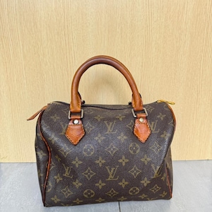 Könnte beinhalten: Braune Handtasche mit Monogramm, Ledergriffen und -besatz. Die Tasche hat einen Reißverschluss und ist mit dem charakteristischen Logomuster der Marke verziert. Die Tasche hat eine klassische, strukturierte Form und eine Vintage-Ästhetik.