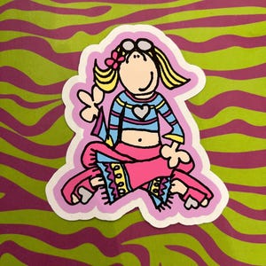 Op de afbeelding: Een kleurrijke sticker met een cartoonfiguur in een zittende pose. De figuur heeft blond haar, een zonnebril en een roze strik. De figuur draagt een blauw-roze gestreepte top met een hart en een roze broek. De achtergrond is een groen en paars zebra streepjespatroon.