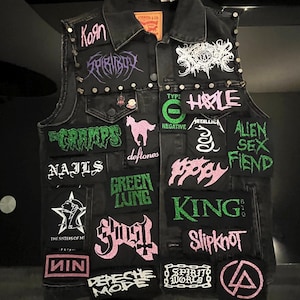 May include: A white ceramic mug with a black handle and the text "But First, Coffee" in a bold, black font. The mug is set against a blurred background, suggesting a cozy setting.